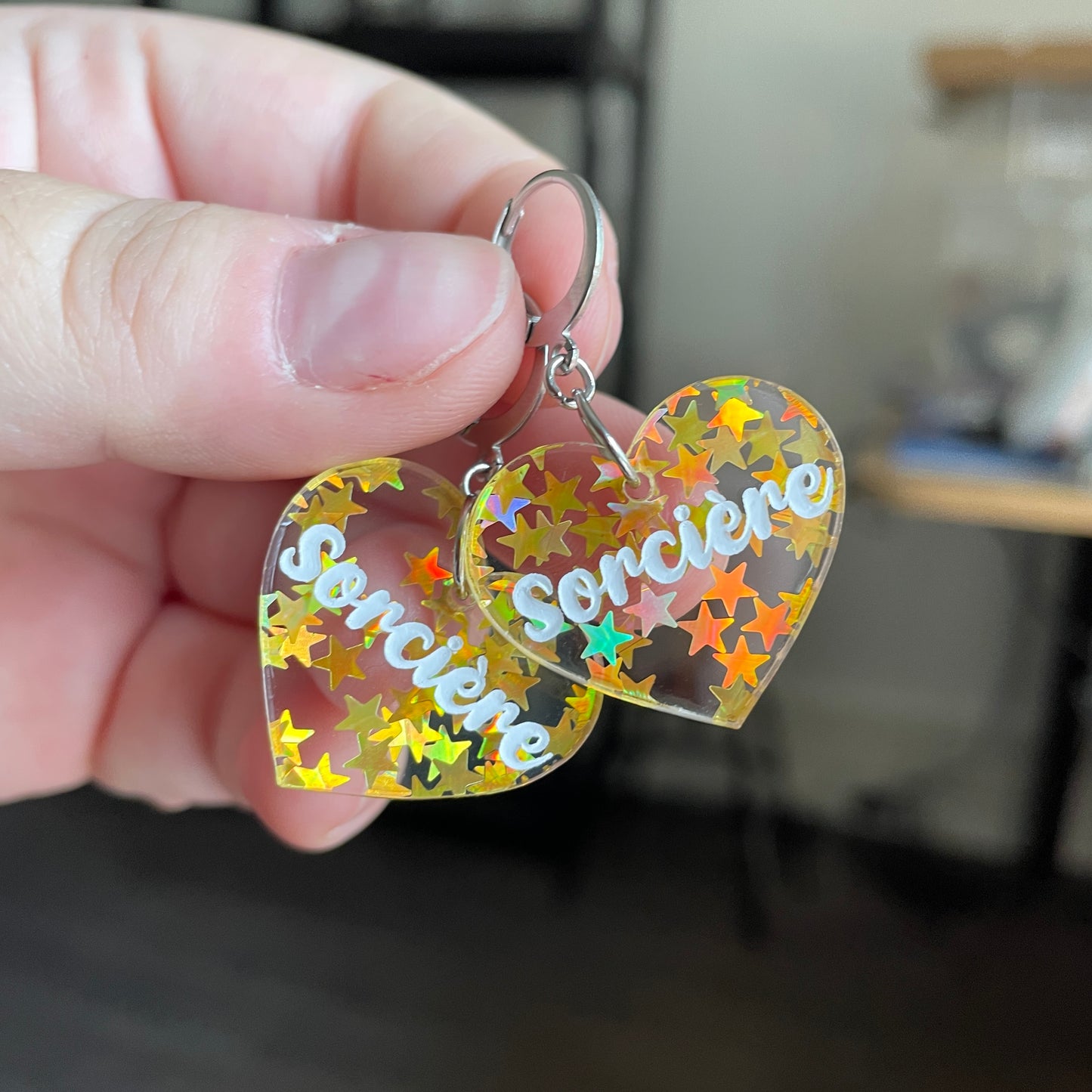 Petites boucles d'oreilles coeurs pendantes "Sorcière" en acrylique transparente avec des confettis étoiles dorées
