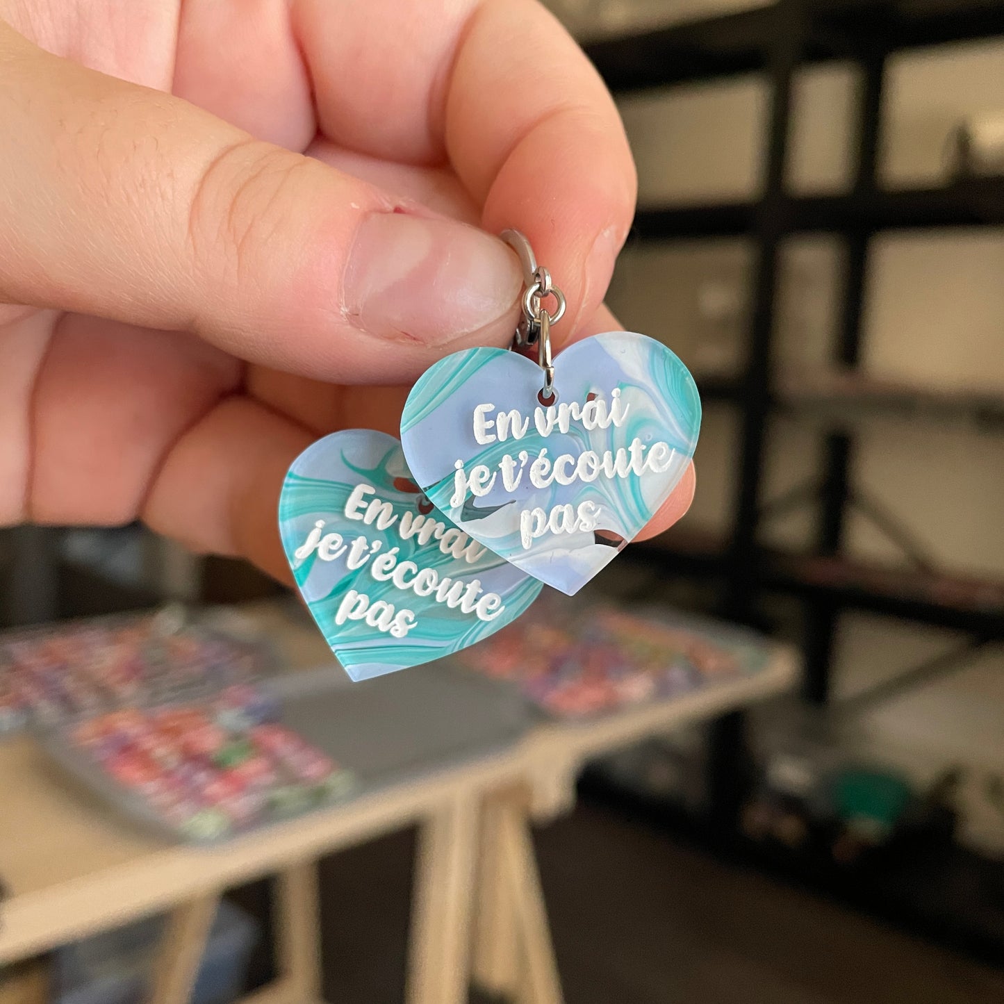 Petites boucles d'oreilles coeurs pendantes "En vrai je t'écoute pas" en acrylique semi transparente marbrée bleue, verte et blanche