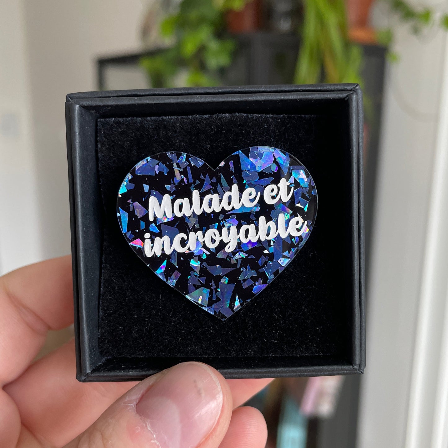 Broche "Malade et incroyable" en acrylique noire à gros confettis bleus galactiques