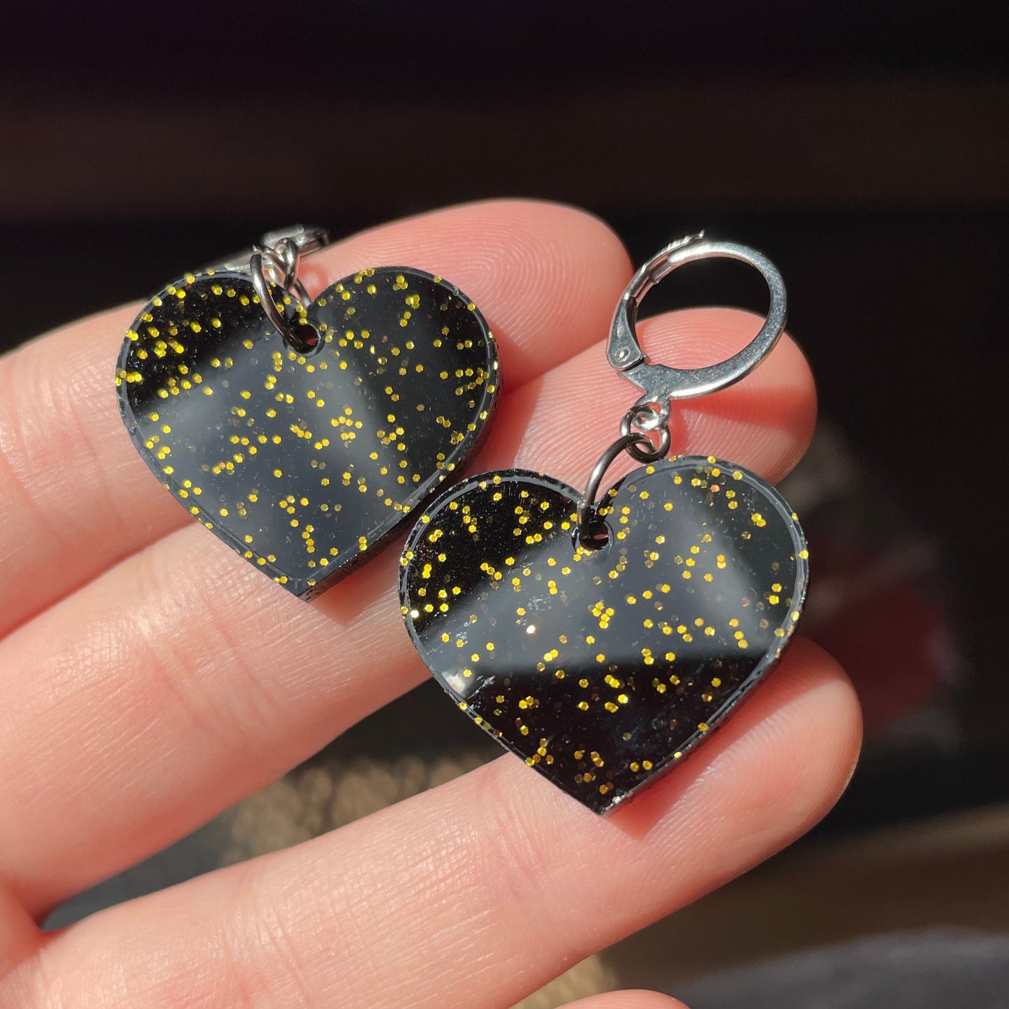 Petites boucles d'oreilles coeurs pendantes en acrylique noire avec des paillettes dorées