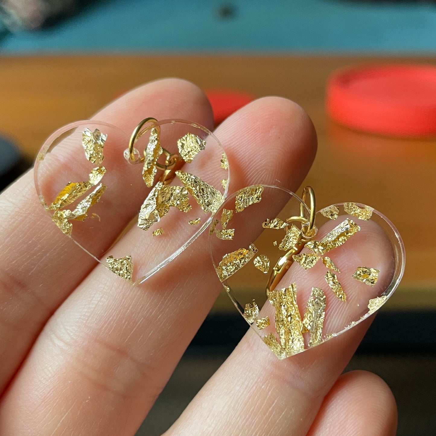 Petites boucles d'oreilles coeurs pendantes en acrylique transparente avec des éclats de feuilles dorées