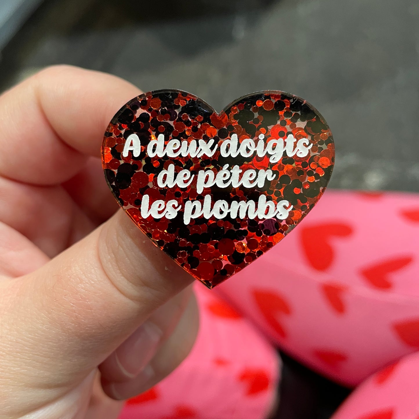 Broche "A deux doigts de péter les plombs" en acrylique semi-transparente avec des pois rouges et noirs