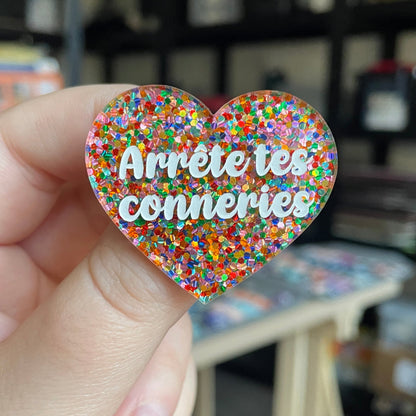 Broche "Arrête tes conneries" en acrylique avec des confettis multicolores
