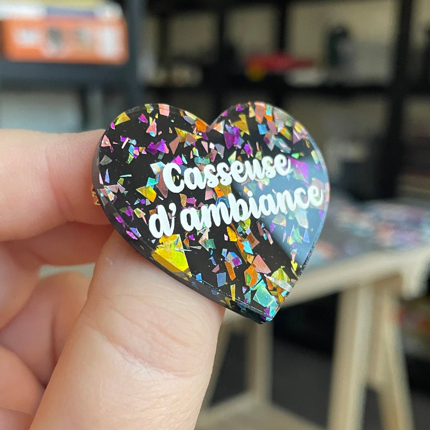 Broche "Casseuse d'ambiance" en acrylique noire avec des éclats de confettis multicolores