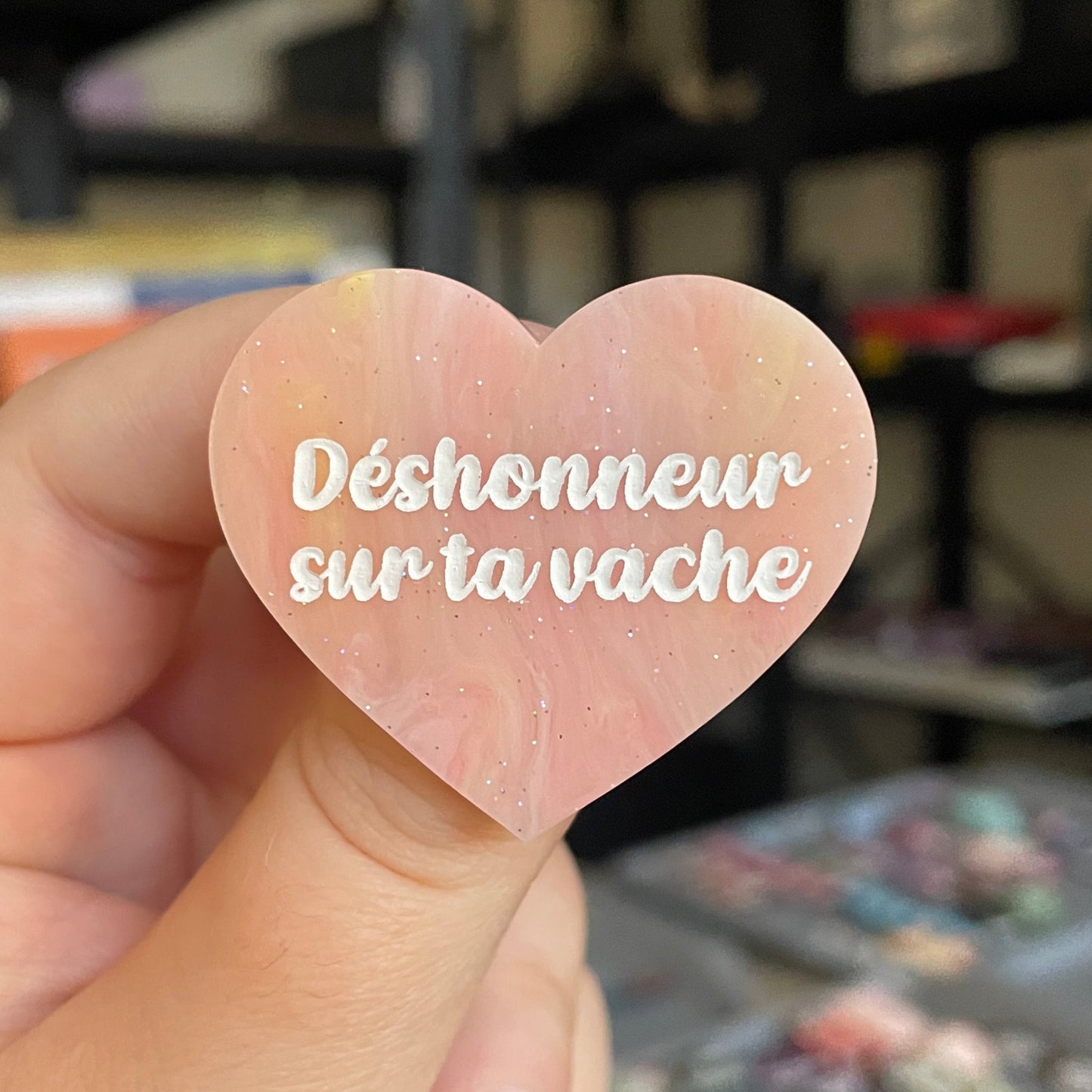 Broche "Déshonneur sur ta vache" en acrylique marbrée semi-transparente orange, corail, blanche et jaune à paillettes