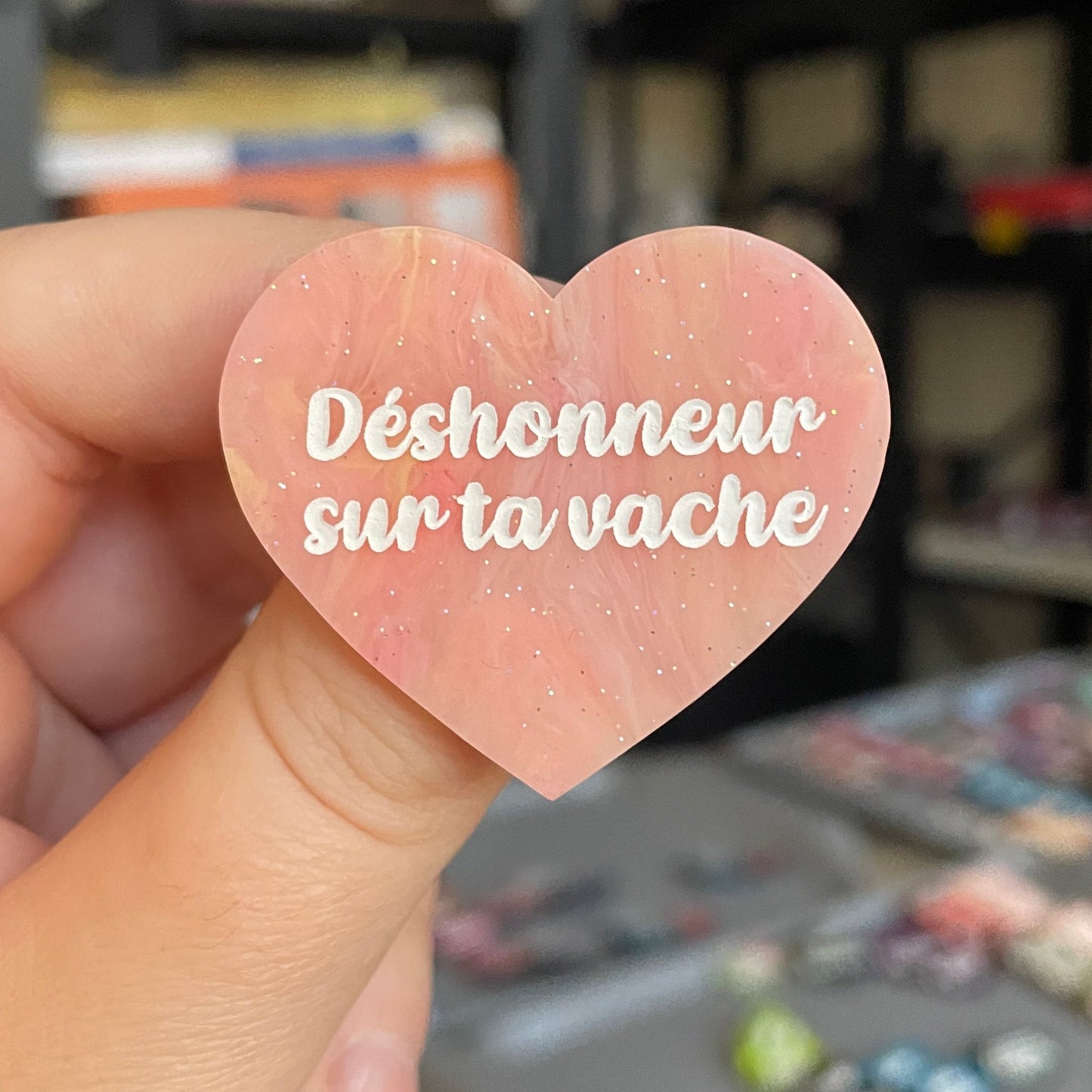 Broche "Déshonneur sur ta vache" en acrylique marbrée semi-transparente orange, corail, blanche et jaune à paillettes