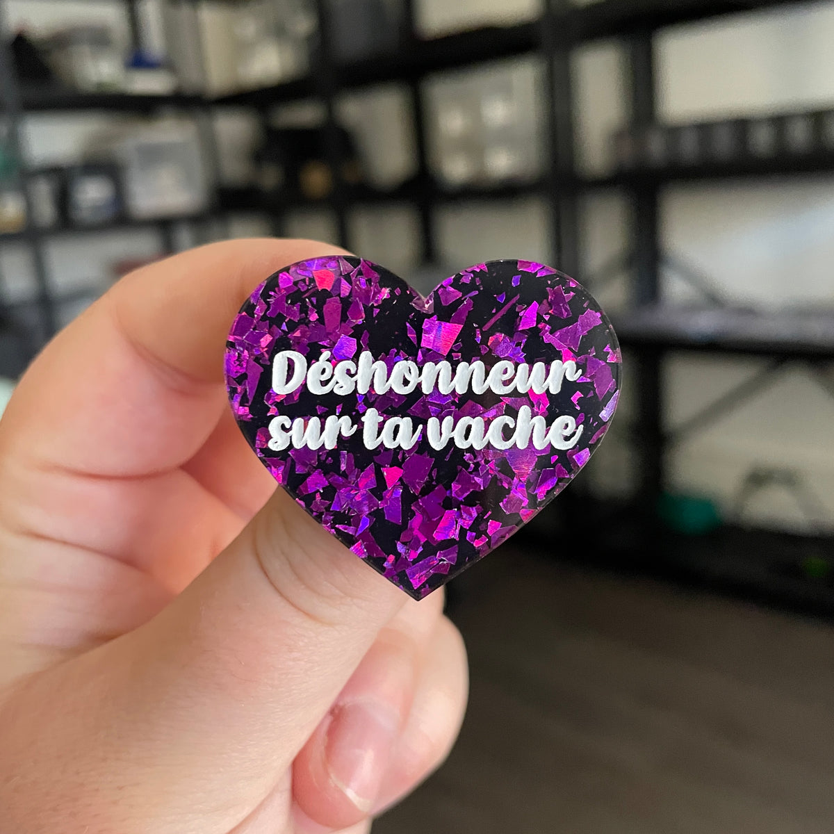 Broche "Déshonneur sur ta vache" en acrylique noire avec des éclats de confettis violets