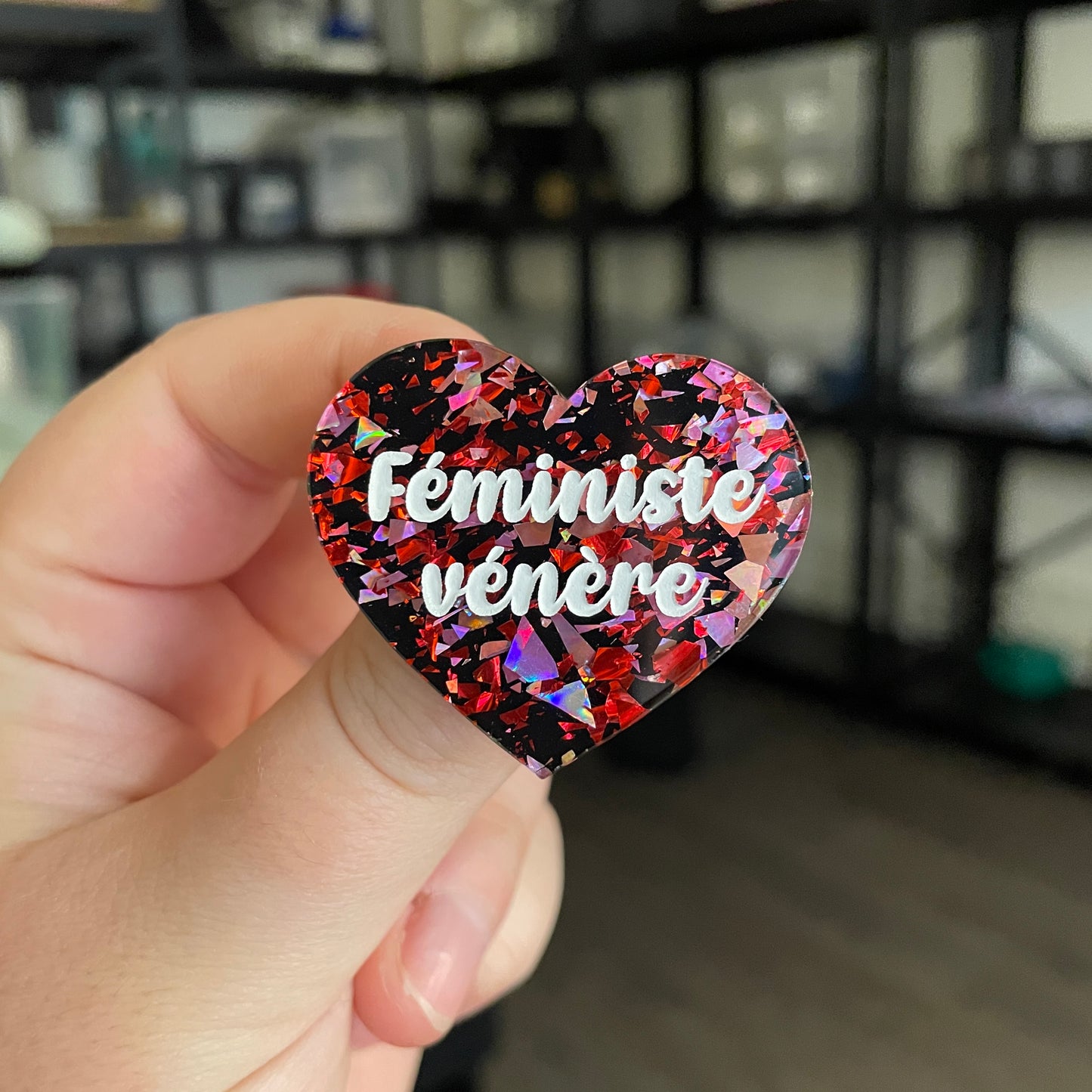 Broche "Féministe vénère" en acrylique noire avec des éclats de confettis rouges et roses
