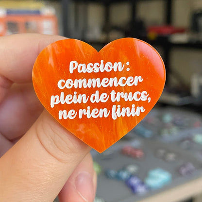 Broche "Passion : commencer plein de trucs, ne rien finir" en acrylique marbrée orange et dorée à paillettes