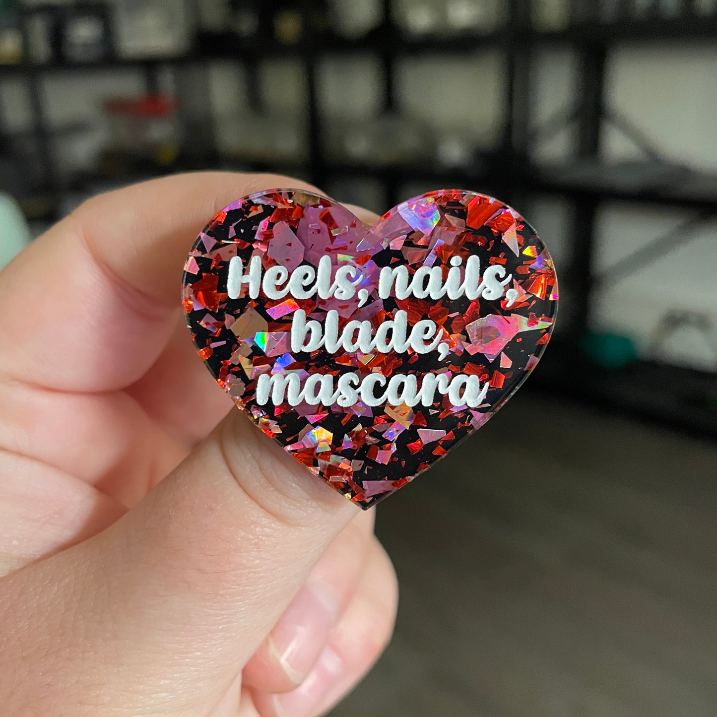 [CONTRÔLE TECHNIQUE] Broche "Heels, nails, blade, mascara" en acrylique noire avec des éclats de confettis rouges et roses