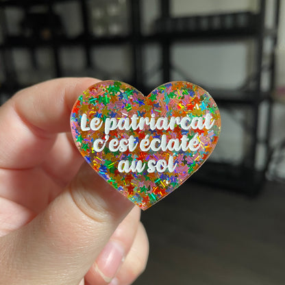 [CONTRÔLE TECHNIQUE] Broche "Le patriarcat c'est éclaté au sol" en acrylique semi transparente avec des confettis étoiles multicolores
