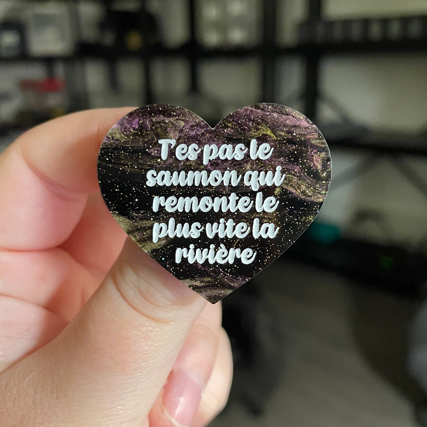 [CONTRÔLE TECHNIQUE] Broche "T'es pas le saumon qui remonte le plus vite la rivière" en acrylique marbrée noire, violette et dorée à paillettes