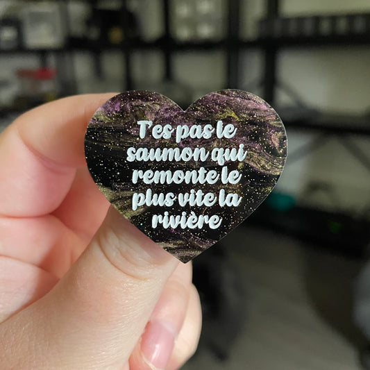 [CONTRÔLE TECHNIQUE] Broche "T'es pas le saumon qui remonte le plus vite la rivière" en acrylique marbrée noire, violette et dorée à paillettes