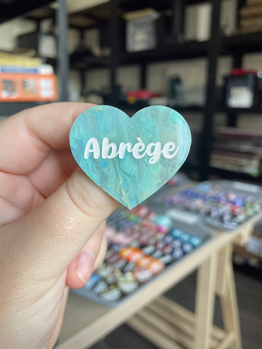 [CONTRÔLE TECHNIQUE] Broche "Abrège" en acrylique marbrée semi-transparente bleue, turquoise, blanche et jaune à paillettes