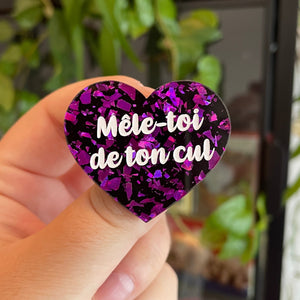 Broche "Mêle-toi de ton cul" en acrylique noire avec des éclats de confettis violets