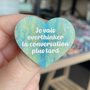[CONTRÔLE TECHNIQUE] Broche "Je vais overthinker la conversation plus tard" en acrylique marbrée semi-transparente bleue, turquoise, blanche et jaune à paillettes
