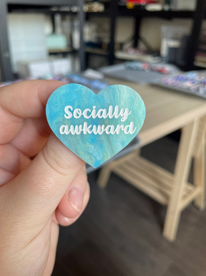 [CONTRÔLE TECHNIQUE] Broche "Socially awkward" en acrylique marbrée semi-transparente bleue, turquoise, blanche et jaune à paillettes