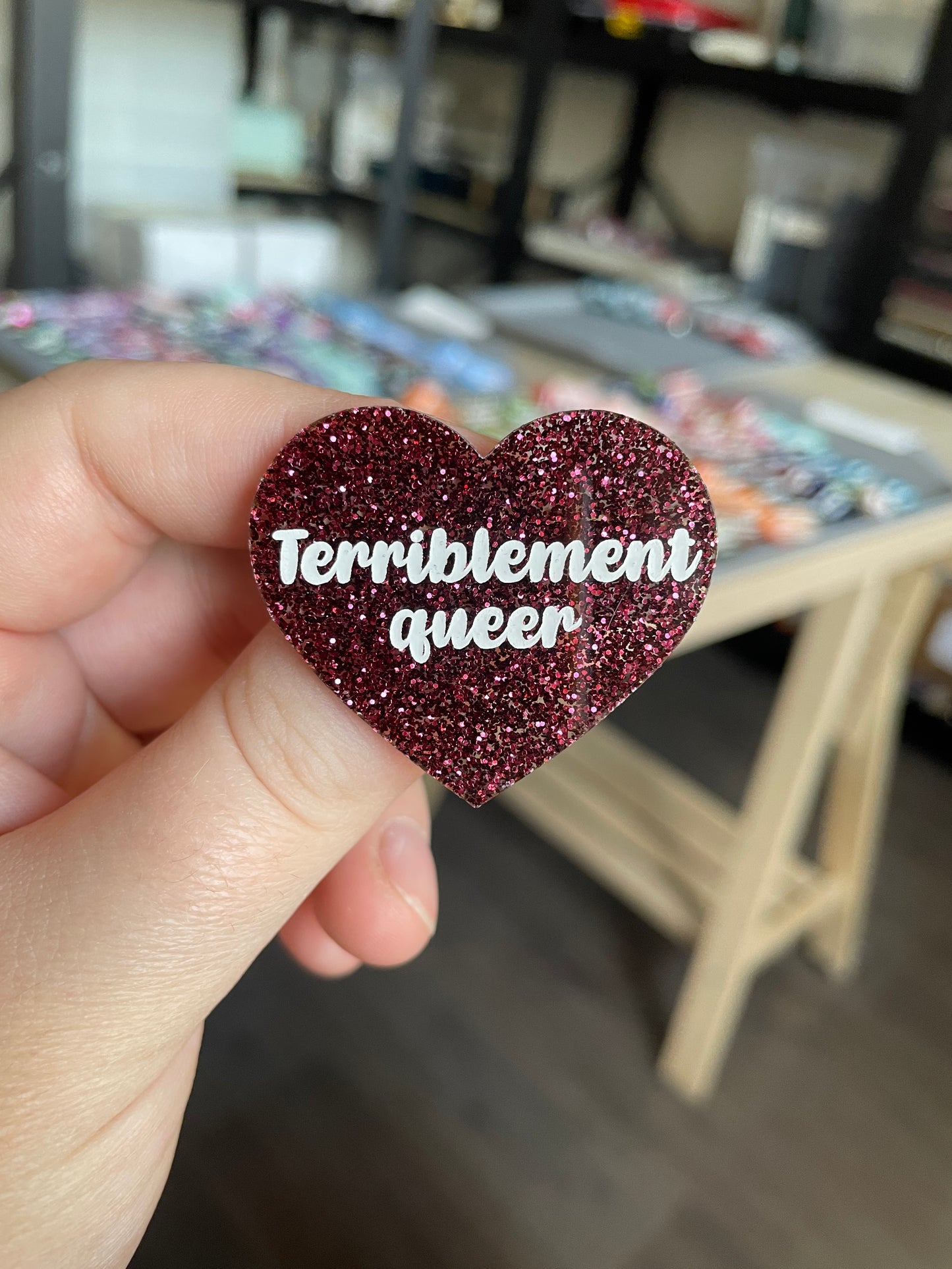 [CONTRÔLE TECHNIQUE] Broche "Terriblement queer" en acrylique à paillettes bordeaux