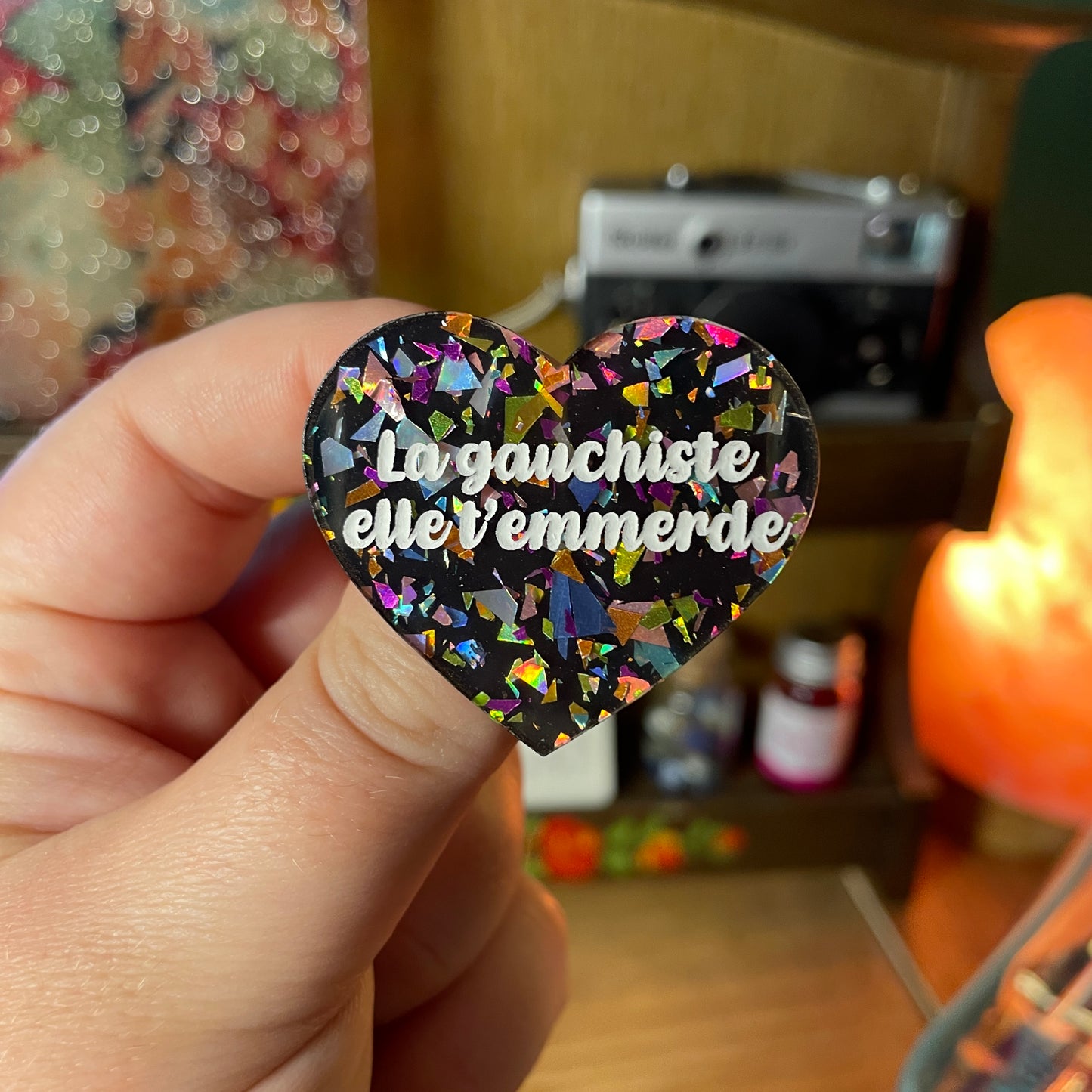 Broche "La gauchiste elle t'emmerde" en acrylique noire avec des éclats de confettis multicolores