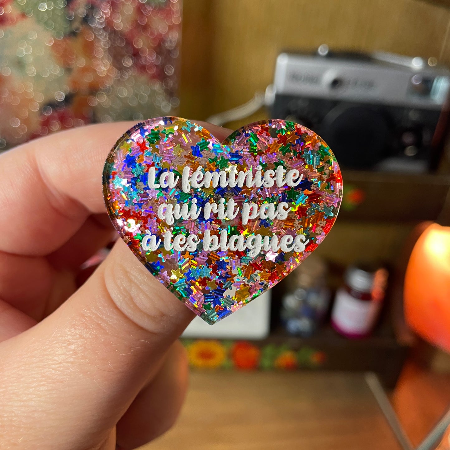 Broche "La féministe qui rit pas à tes blagues" en acrylique semi transparente avec des étoiles multicolores