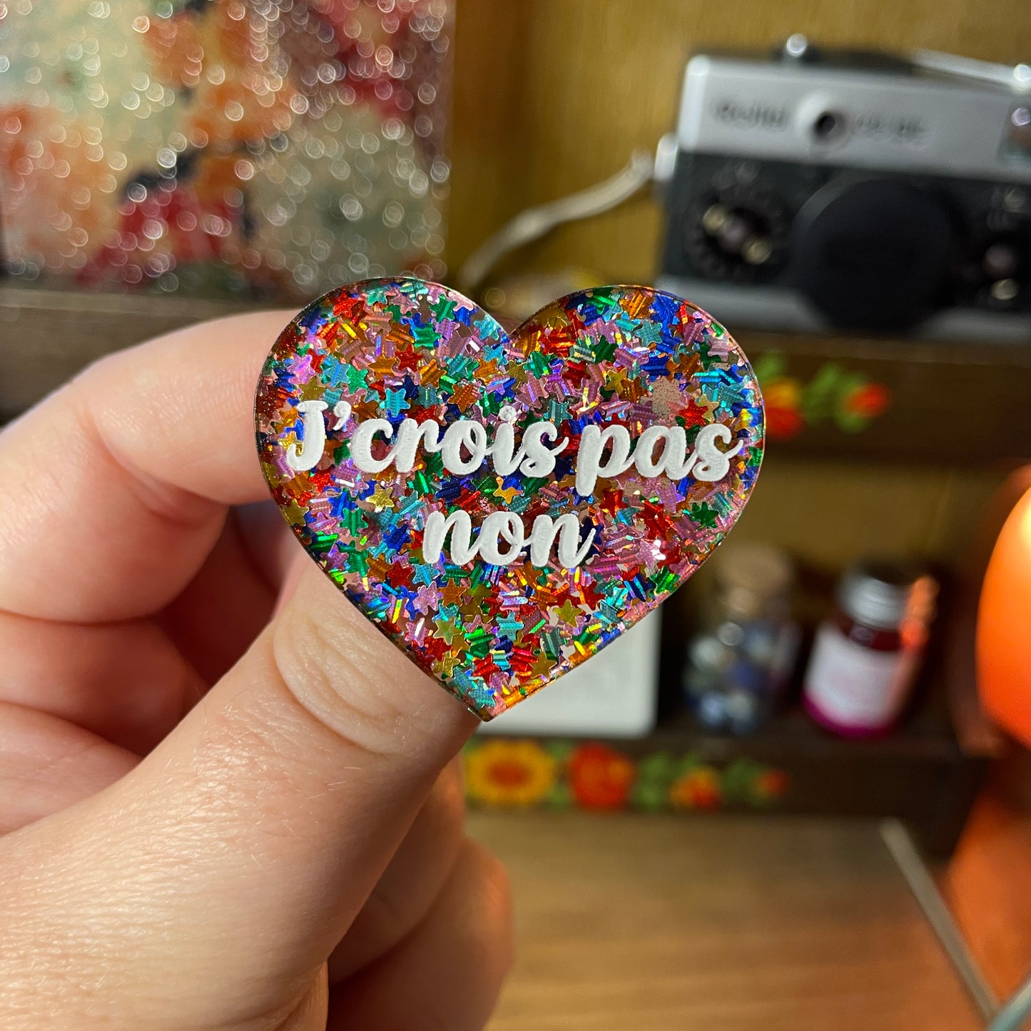 Broche "J'crois pas non" en acrylique semi transparente avec des étoiles multicolores