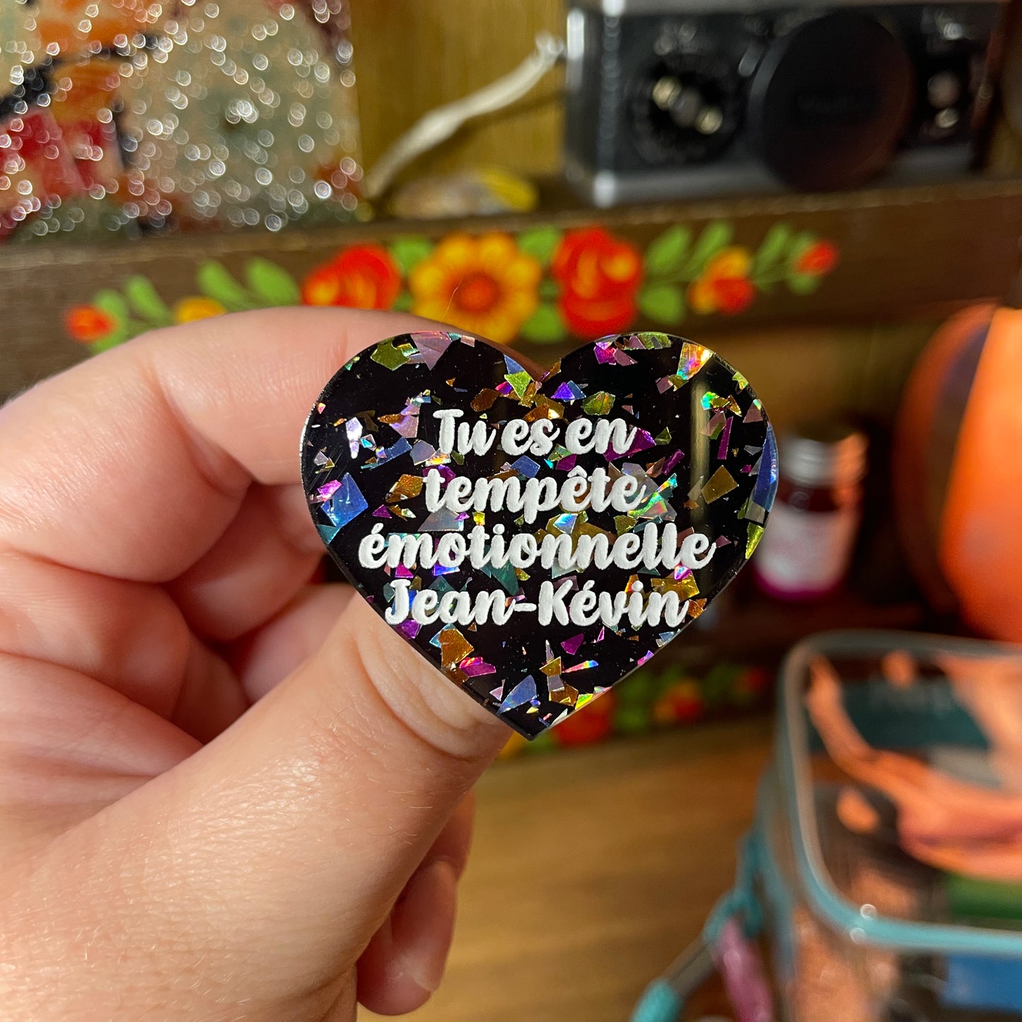 Broche "Tu es en tempête émotionnelle Jean-Kévin" en acrylique noire avec des éclats de confettis multicolores