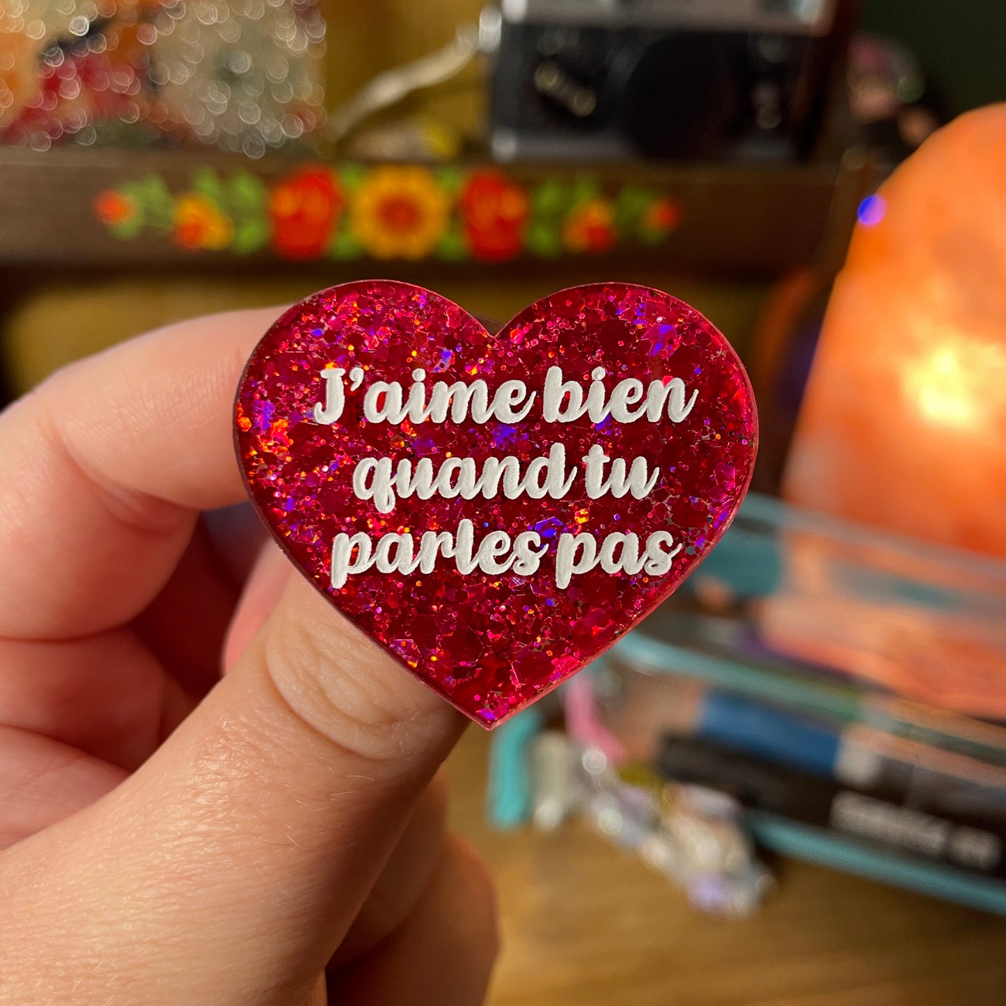 Broche "J'aime bien quand tu parles pas" en acrylique semi transparente à paillettes rouges