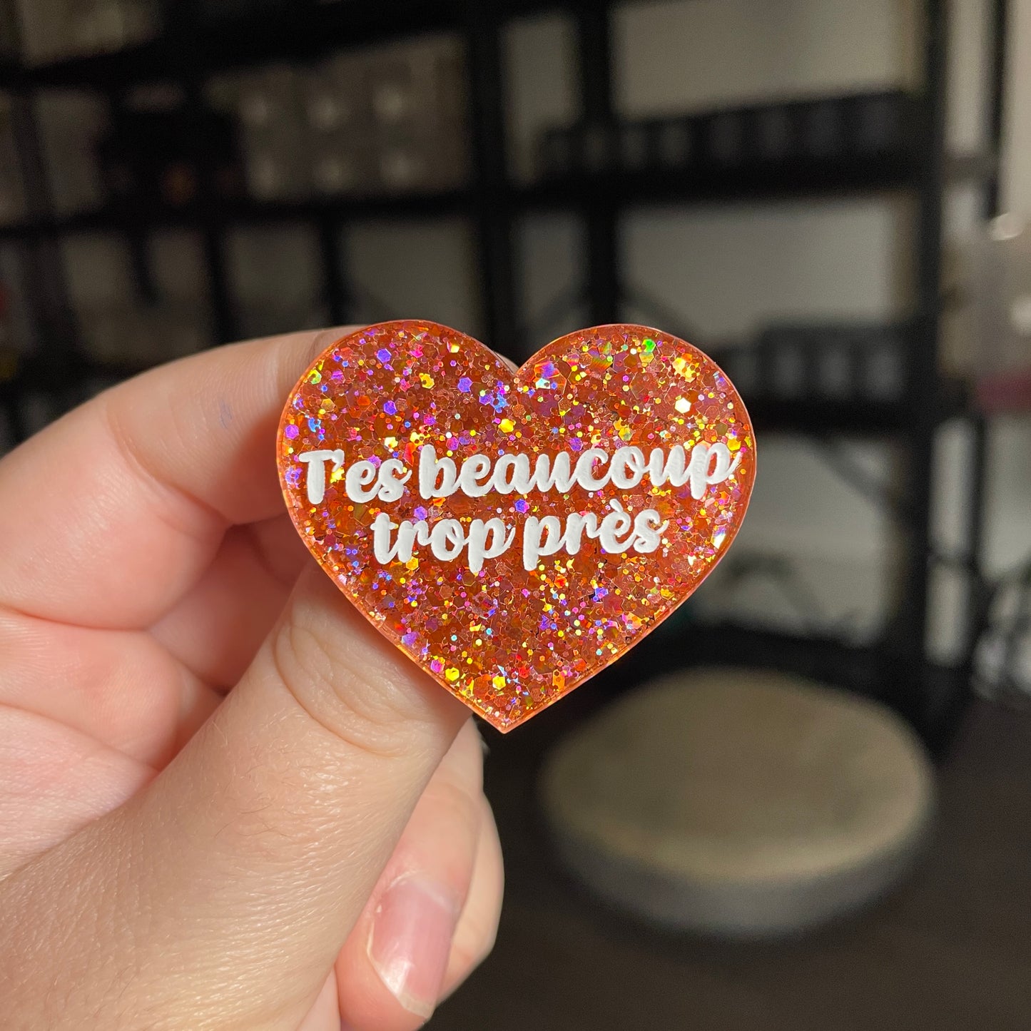 Broche "T'es beaucoup trop près" en acrylique semi transparente avec des paillettes corail