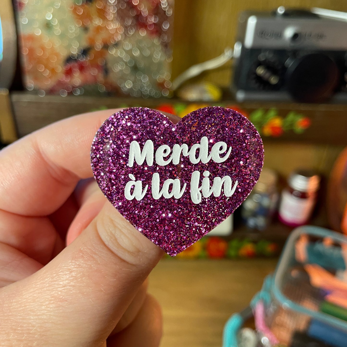 Broche "Merde à la fin" en acrylique à paillettes violettes