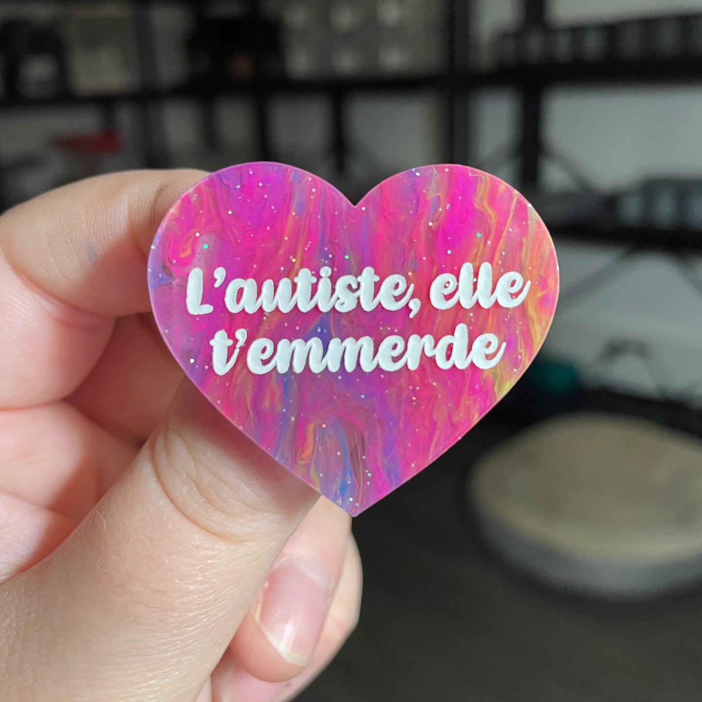 Broche "L'autiste, elle t'emmerde" en acrylique semi transparente marbrée multicolore