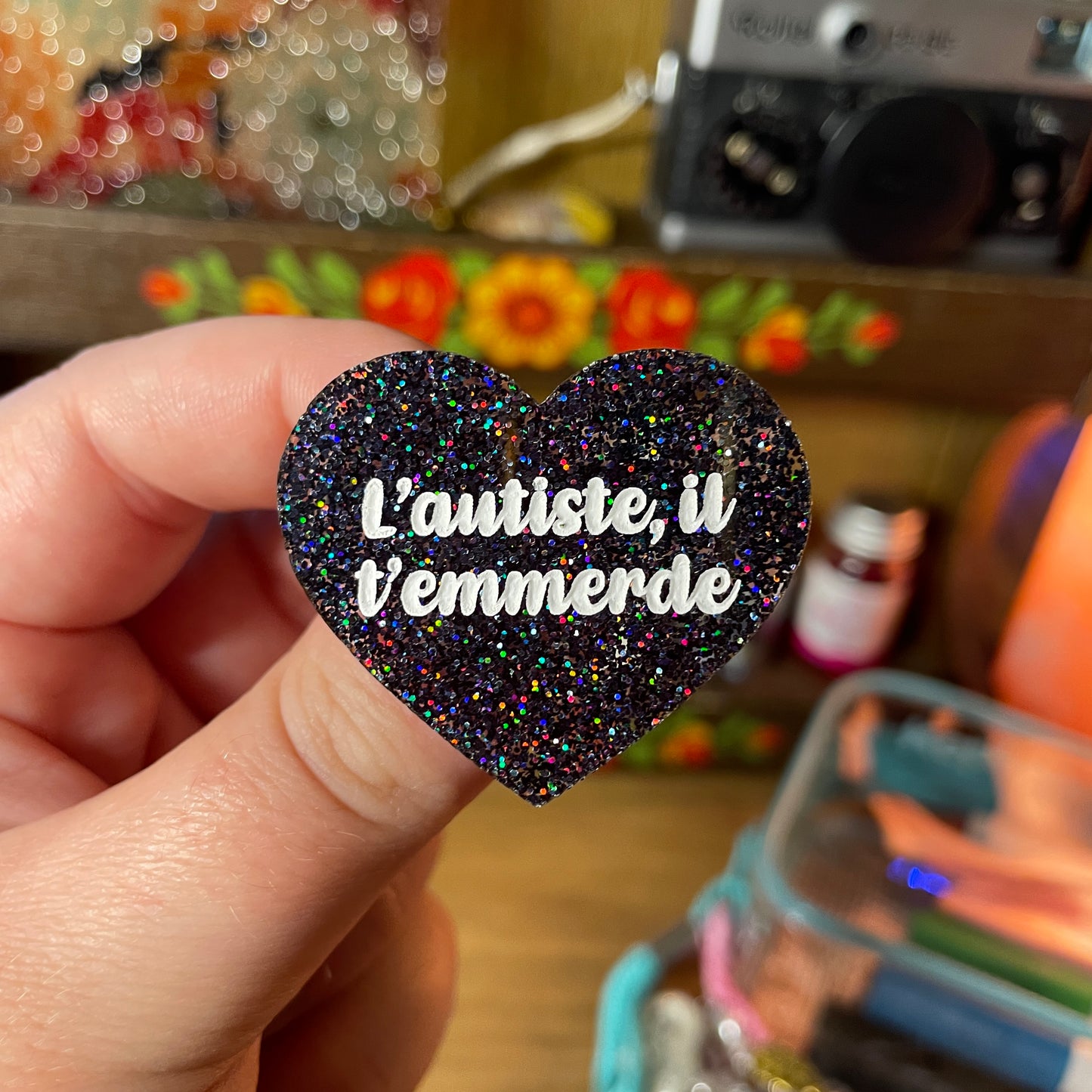 Broche "L'autiste, il t'emmerde" en acrylique à paillettes noires holographiques