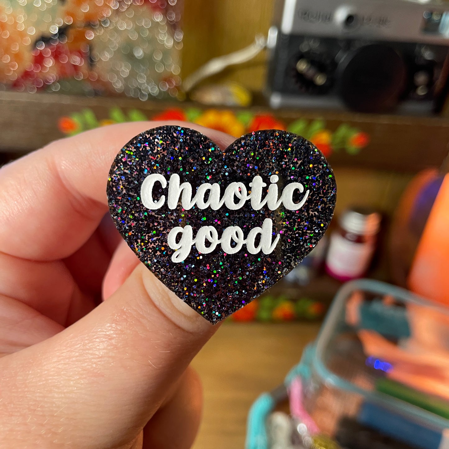 Broche "Chaotic good" en acrylique à paillettes noires holographiques