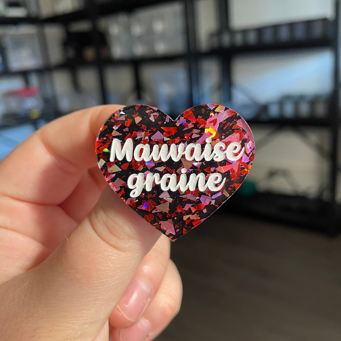 Broche "Mauvaise graine" en acrylique noire avec des éclats de confettis rouges et roses