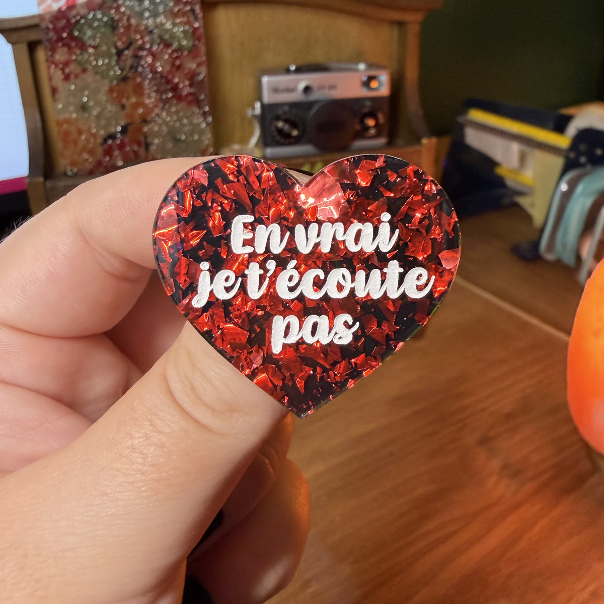 Broche "En vrai je t'écoute pas" en acrylique noire avec des éclats de confettis rouges