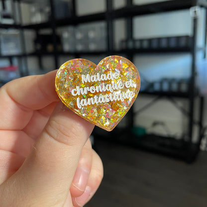 Broche "Malade chronique et fantastique" en acrylique transparente avec des confettis jaunes