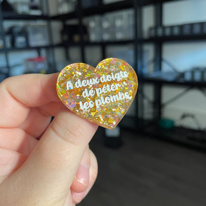 Broche "A deux doigts de péter les plombs" en acrylique transparente avec des confettis jaunes
