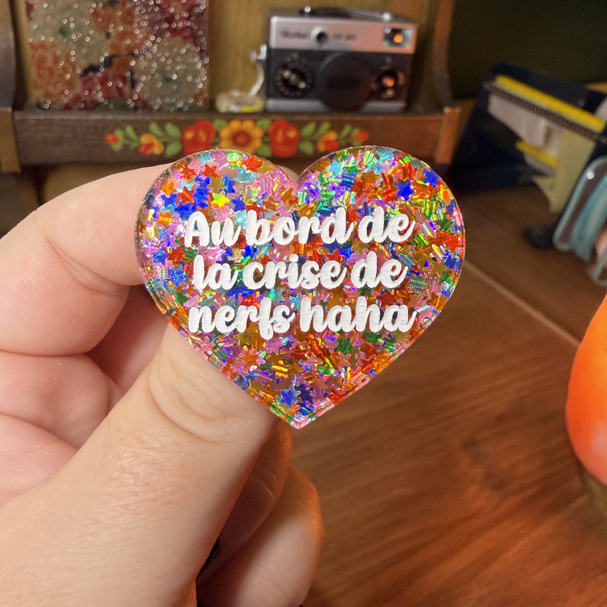 Broche "Au bord de la crise de nerfs haha" en acrylique semi transparente avec des étoiles multicolores