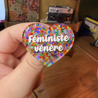 Broche "Féministe vénère" en acrylique semi transparente avec des étoiles multicolores