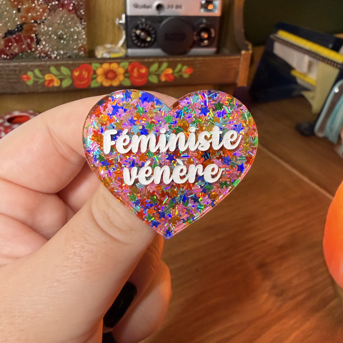 Broche "Féministe vénère" en acrylique semi transparente avec des étoiles multicolores