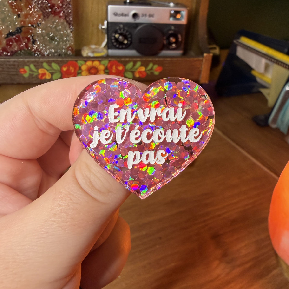 Broche "En vrai je t'écoute pas" en acrylique semi transparente avec des confettis coirail