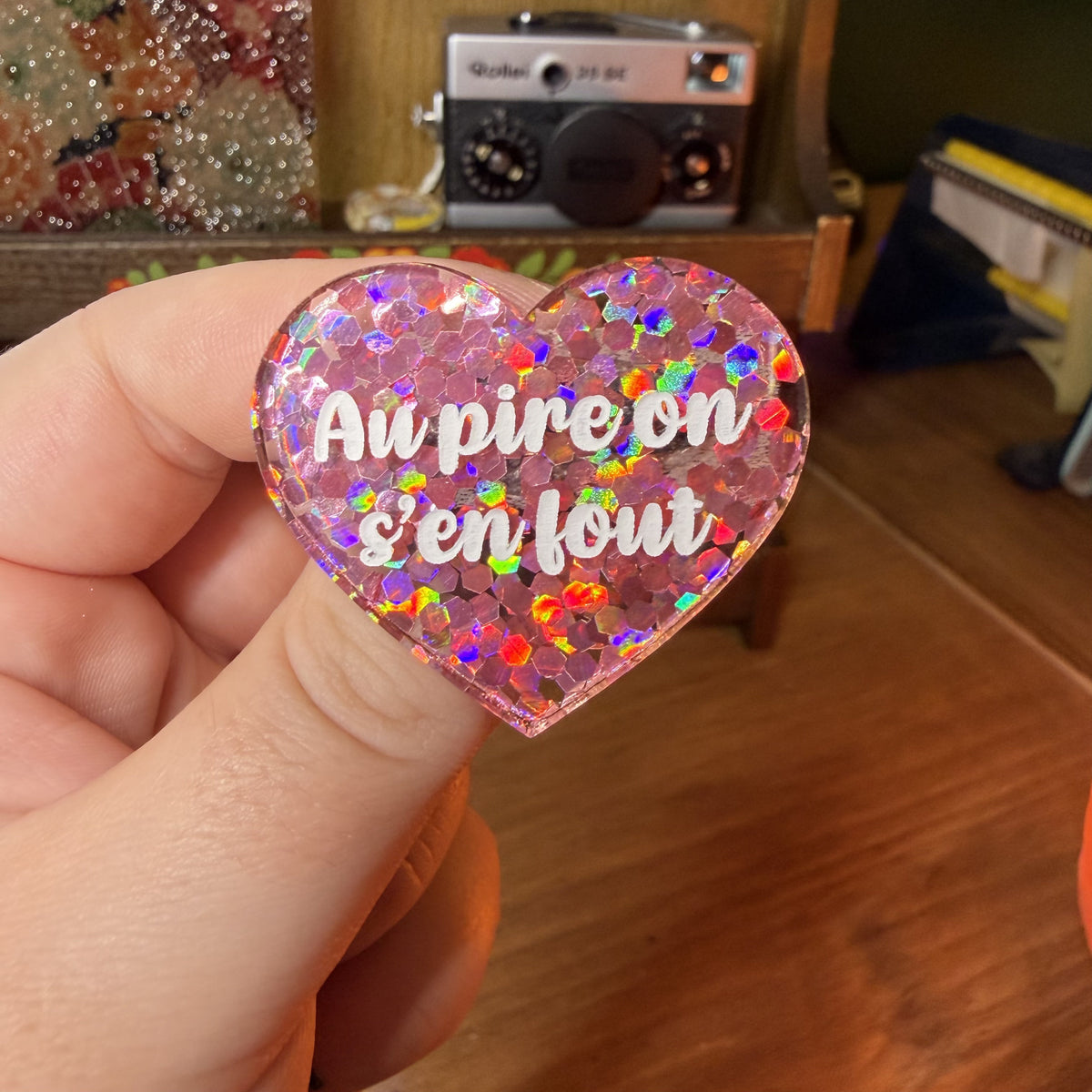 Broche "Au pire on s'en fout" en acrylique semi transparente avec des confettis coirail