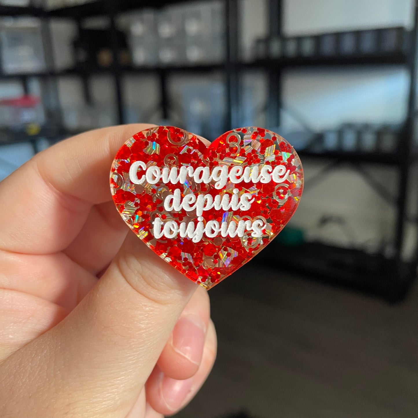 Broche "Courageuse depuis toujours" en acrylique semi transparente avec des confettis rouges et argentés