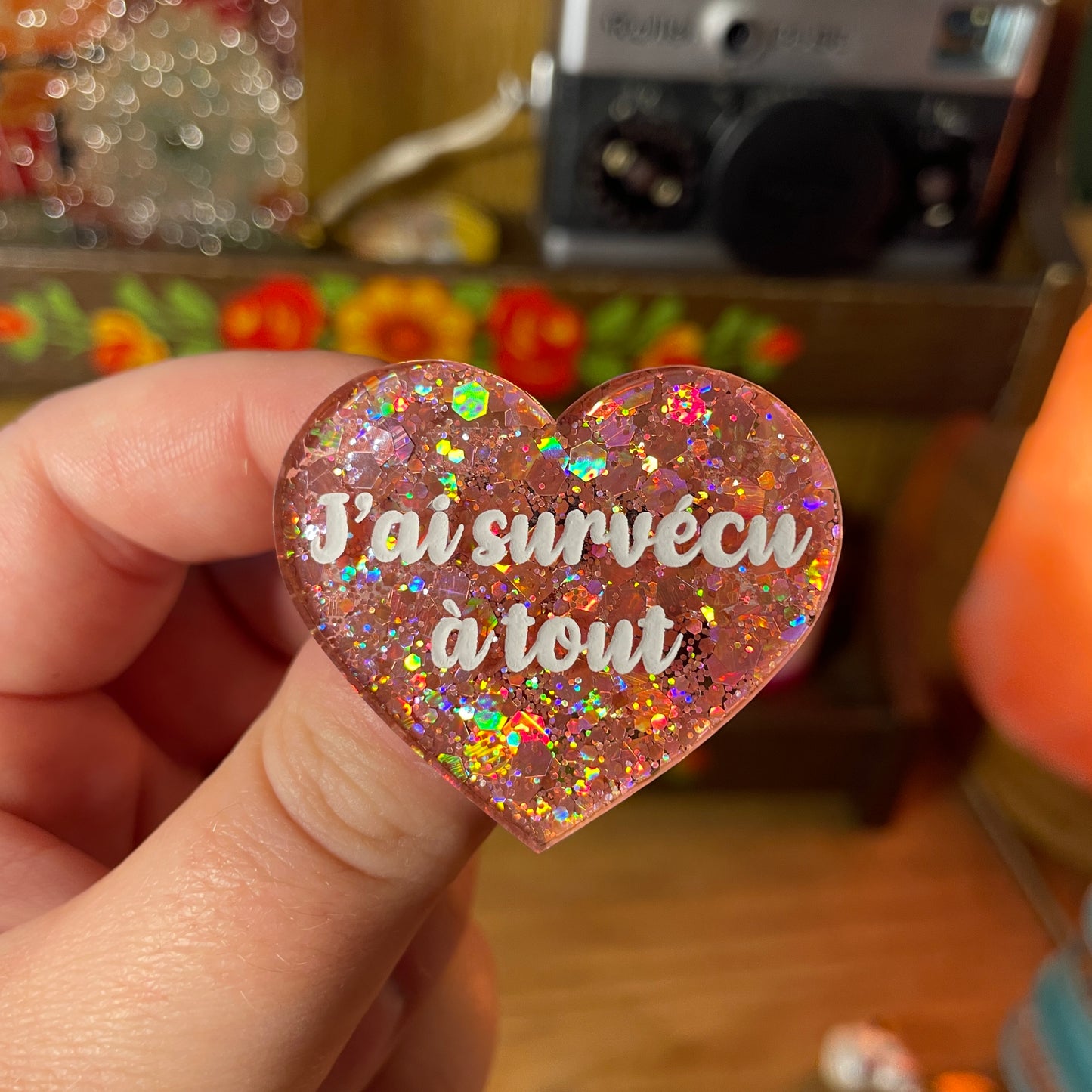 Broche "J'ai survécu à tout" en acrylique semi transparente à paillettes corail