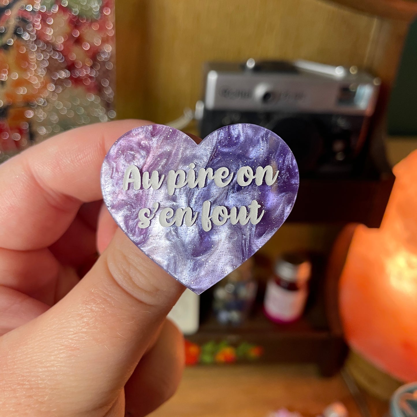Broche "Au pire on s'en fout" en acrylique marbrée bleue, blanche et violette à paillettes