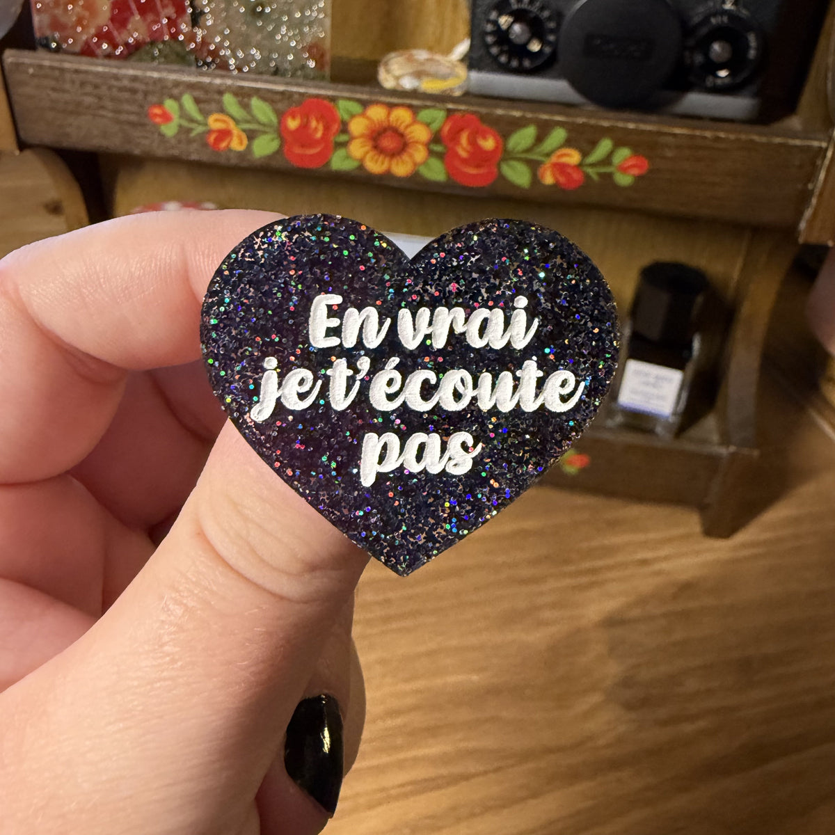 Broche "En vrai je t'écoute pas" en acrylique à paillettes noires holographiques