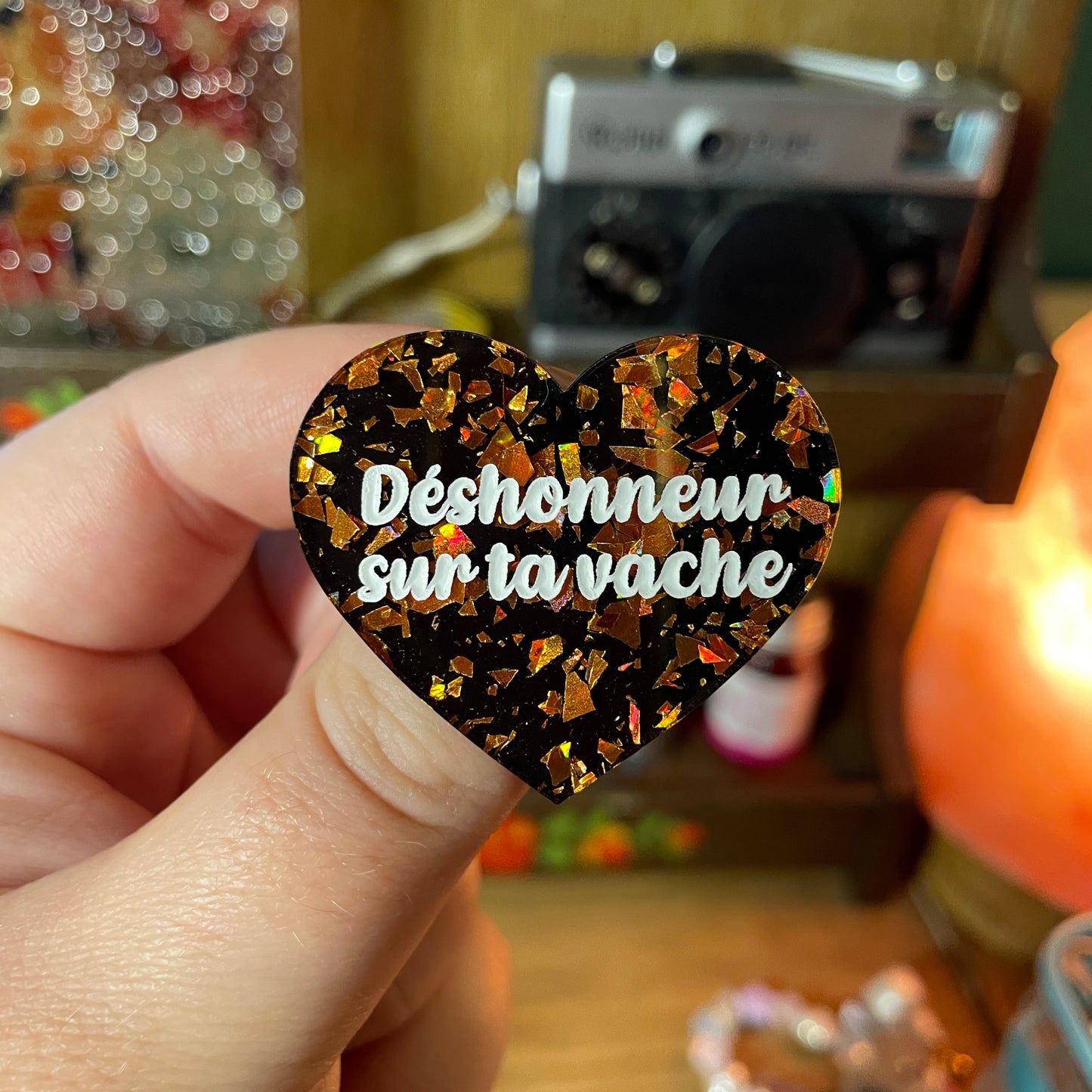 Broche "Déshonneur sur ta vache" en acrylique noire avec des éclats de confettis oranges