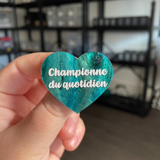 Broche "Championne du quotidien" en acrylique marbrée noire et verte à paillettes
