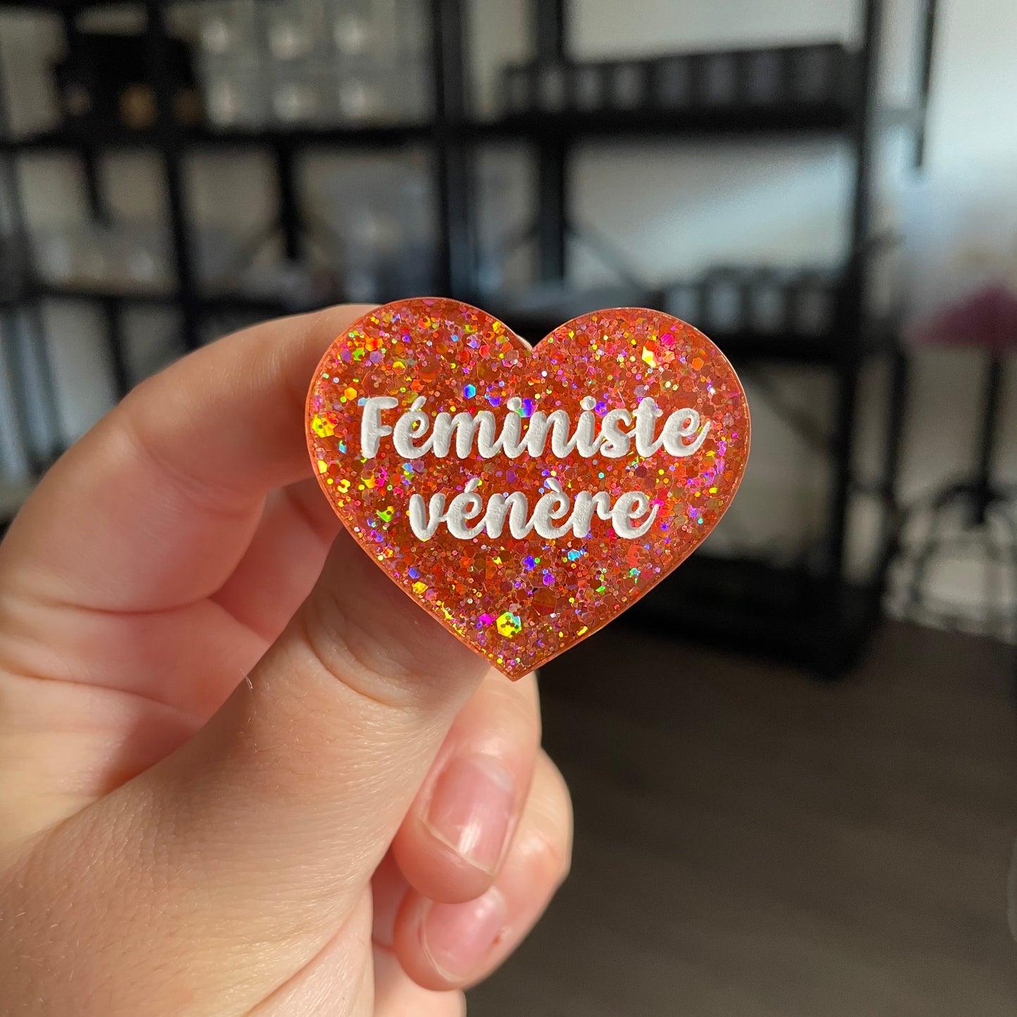 Broche "Féministe vénère" en acrylique semi transparente avec des paillettes corail