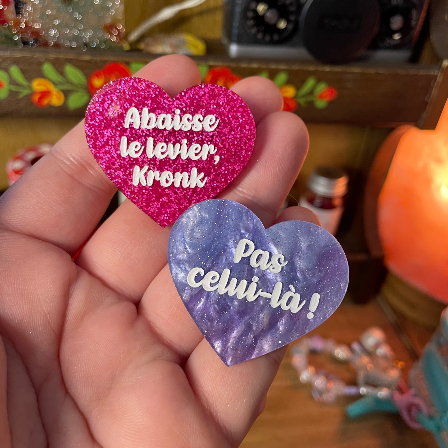 Duo de broches "Abaisse le levier, Kronk !" et "Pas celui-là !" en acrylique à paillettes roses et en acrylique marbrée bleue et violette à paillettes