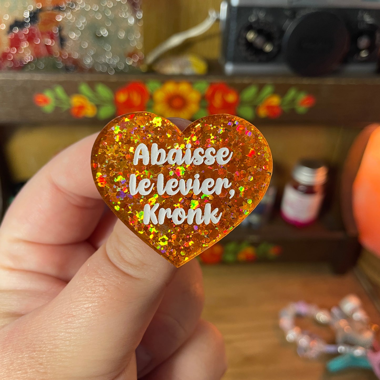 Duo de broches "Abaisse le levier, Kronk !" et "Pas celui-là !" en acrylique semi transparente à paillettes oranges et en acrylique semi transparente à paillettes rouges